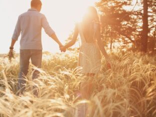 Couple walking through field, sun rays