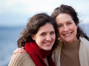 two white women side hugging and smiling at camera